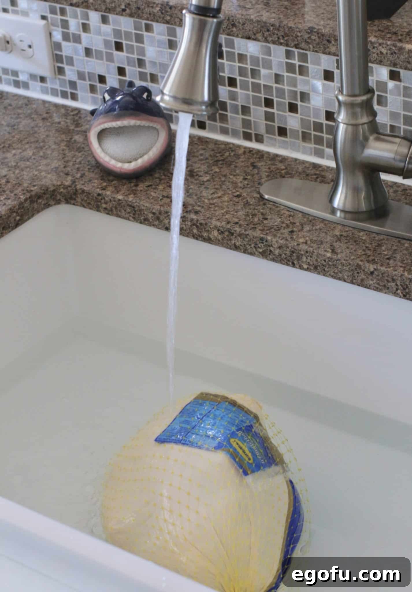 a frozen butterball turkey in a white sink with water streaming on it.