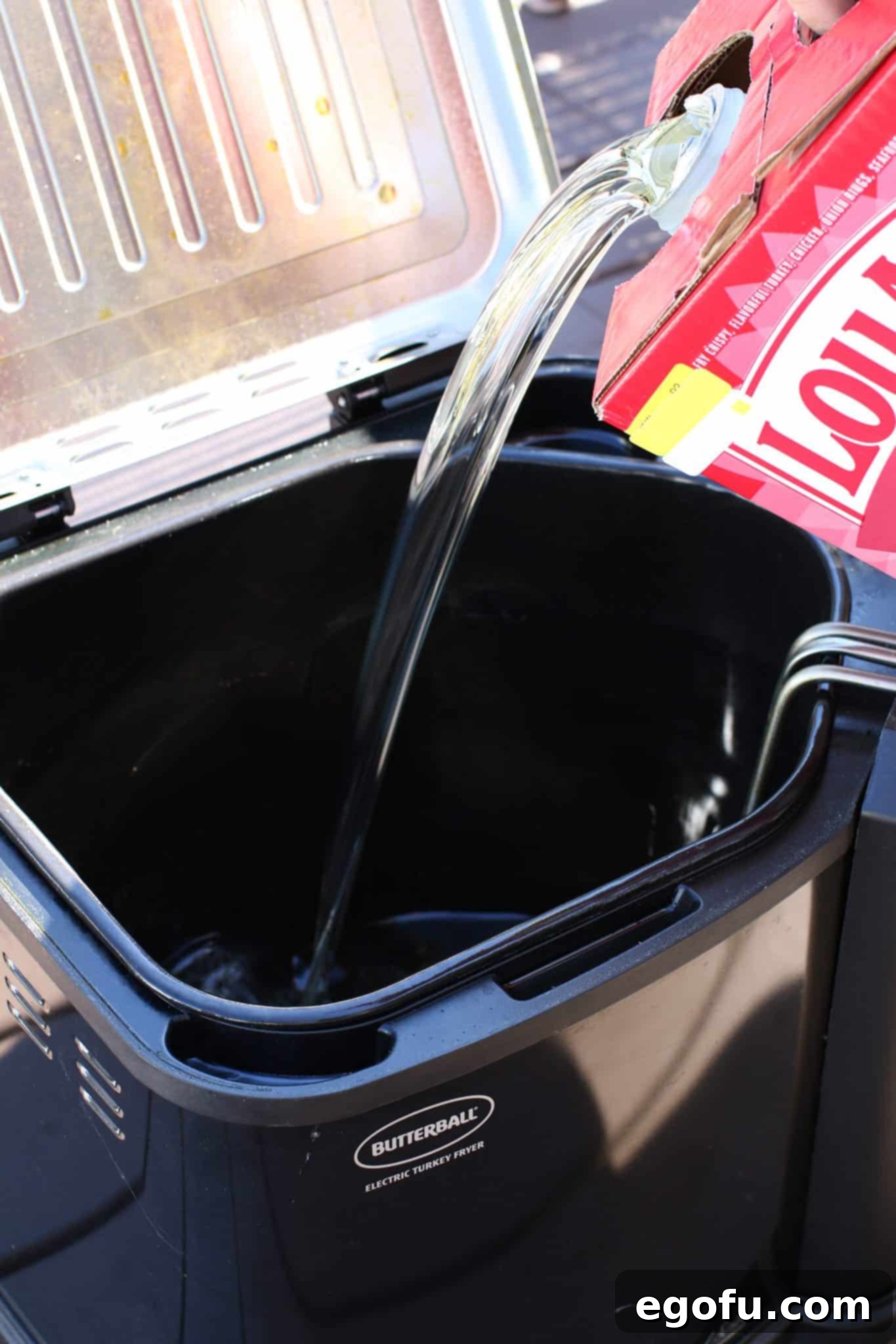 peanut oil being poured into a turkey fryer. 