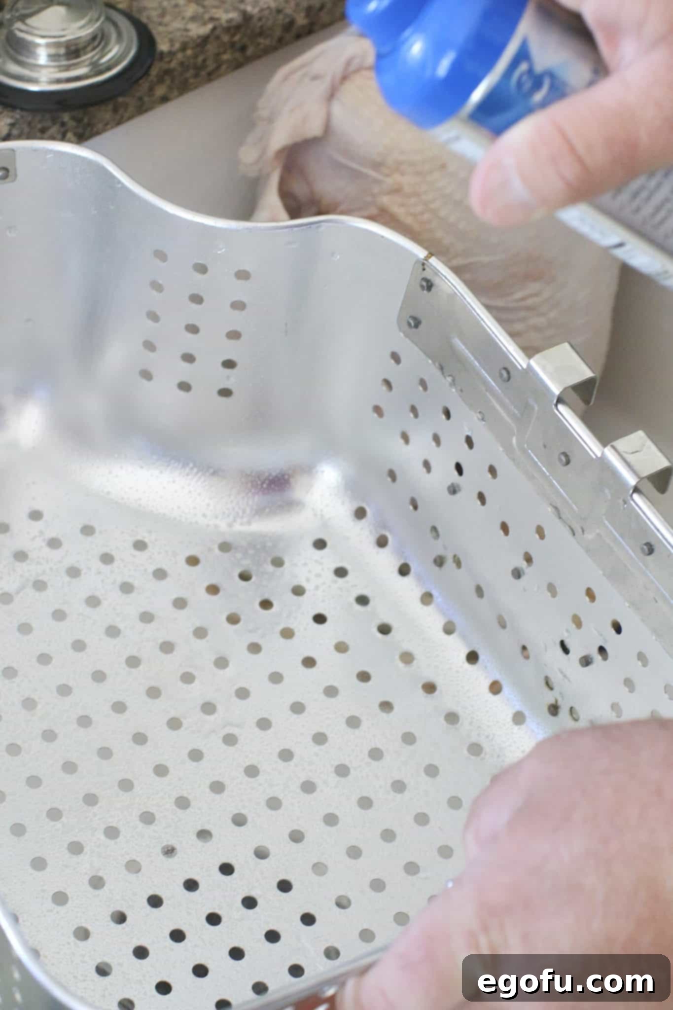 spraying nonstick cooking spray into a turkey fryer basket. 
