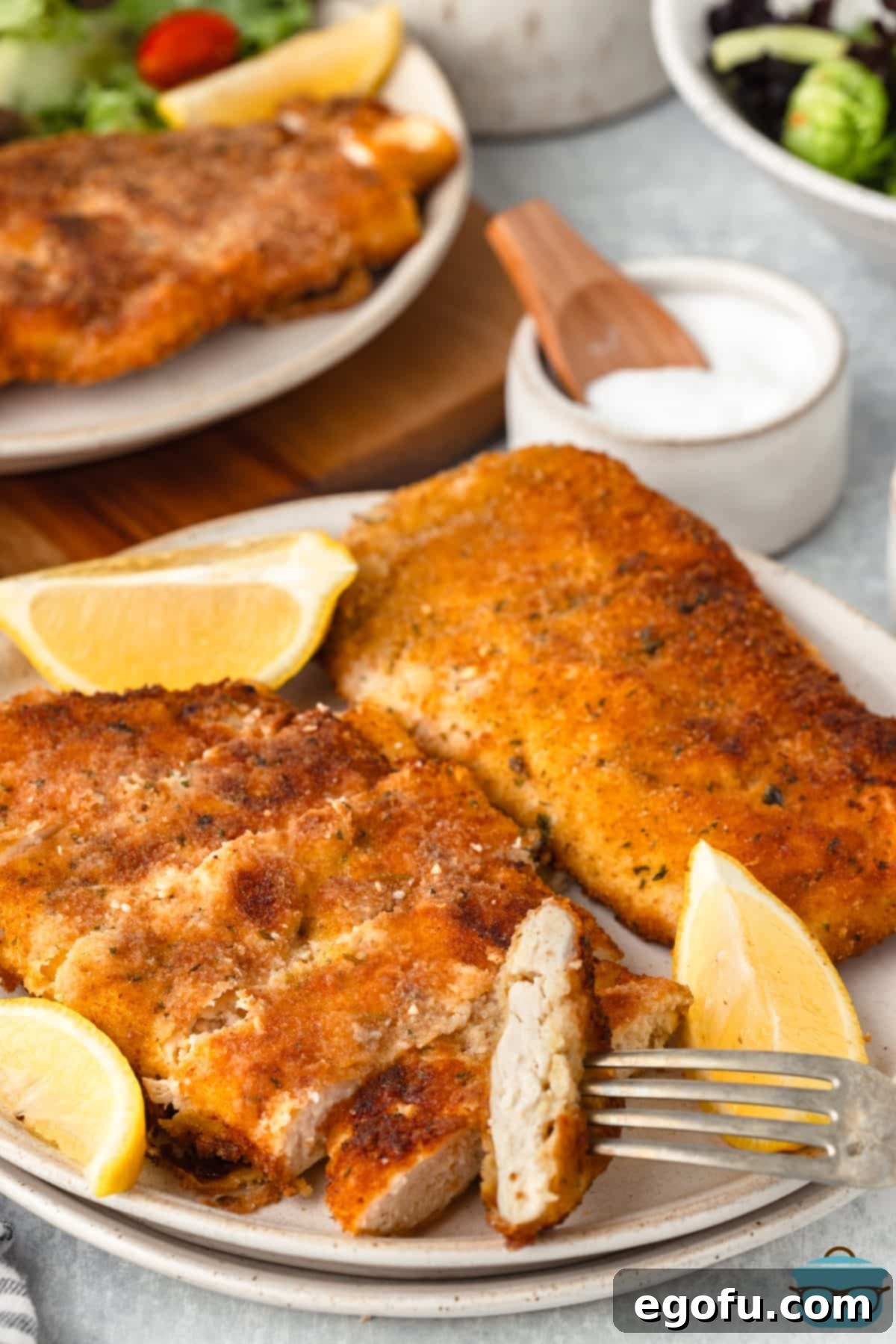 A plate with a Chicken Schnitzel and a fork holding a bite.