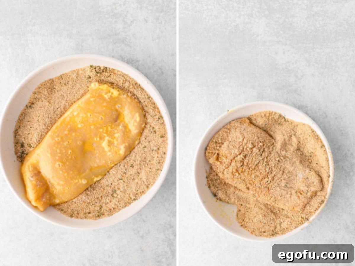 Egg and flour coated chicken in a bowl of bread crumb mixture. 