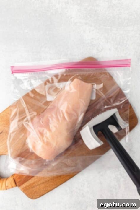 Thin chicken breasts in a Ziplock bag and a meat mallet.