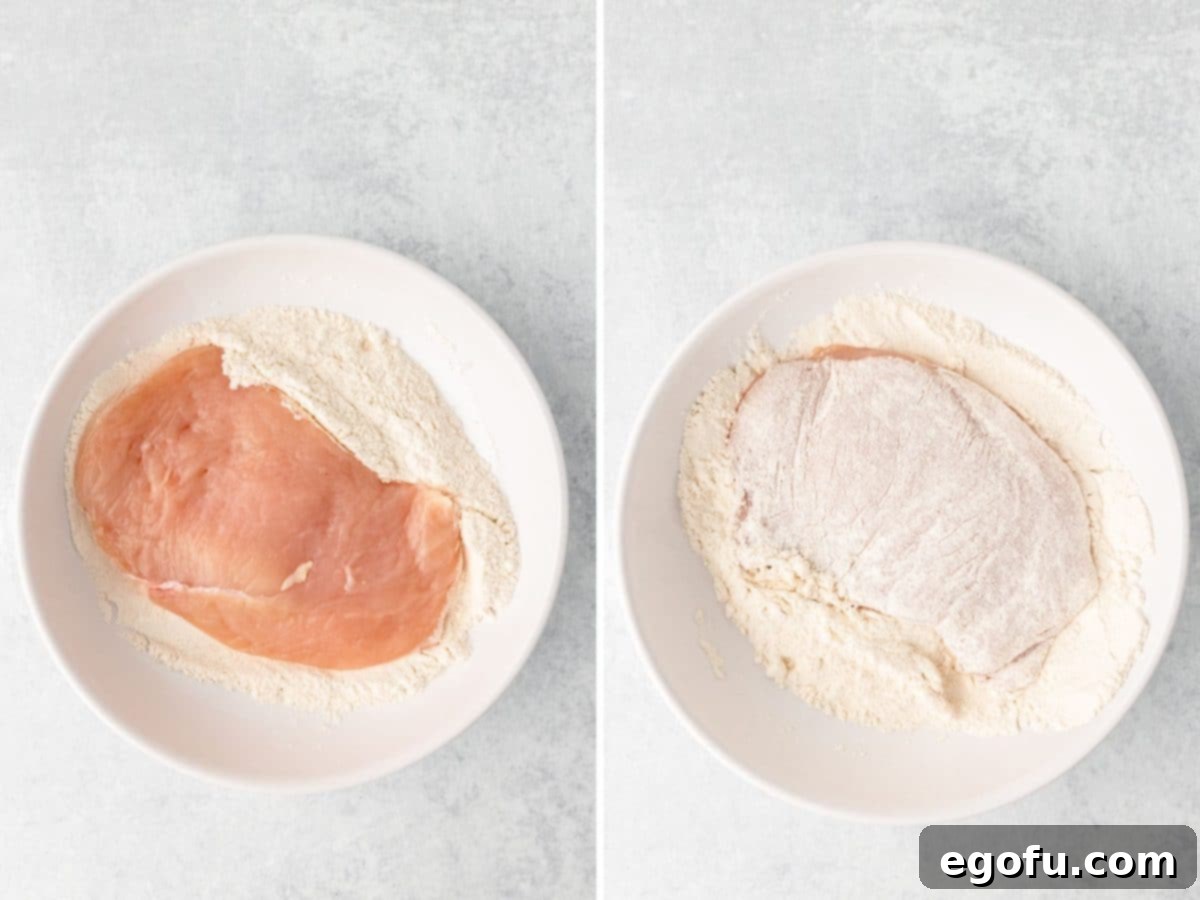 A piece of chicken in a flour mixture. 