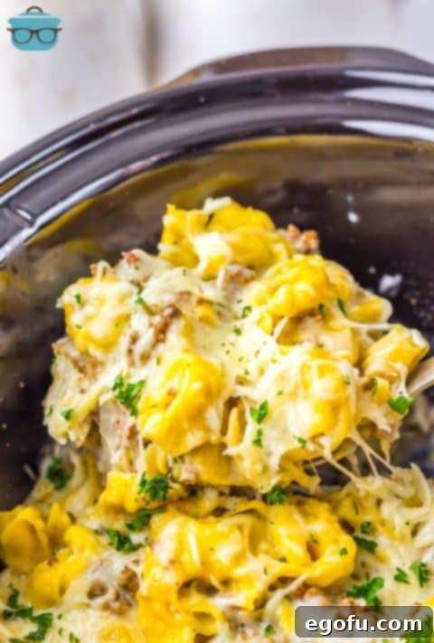 The insert of a Crock Pot with Cheesesteak Tortellini and a scoop being removed.