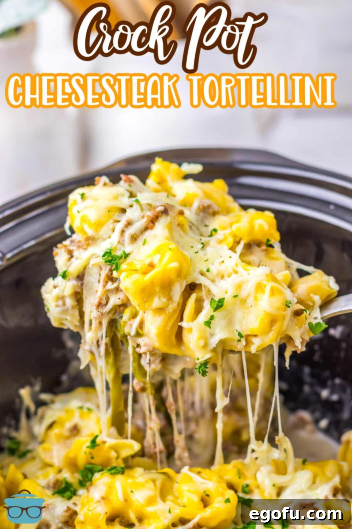A Slow Cooker with a scoop of Cheesesteak Tortellini above it.