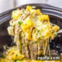 A scoop of Crock Pot Cheesesteak Tortellini above the rest of the Slow Cooker.