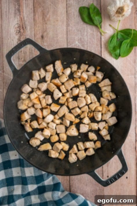 Diced chicken cooking in a skillet.