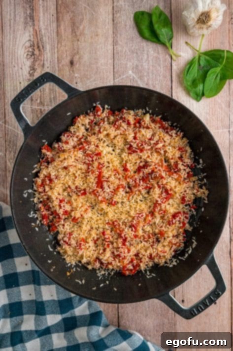 Rice being added to skillet with garlic and tomatoes.