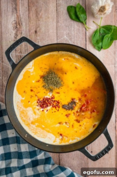 Heavy cream and seasonings being added to a skillet.