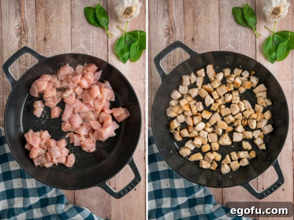 Diced chicken being cooked in a large skillet until golden brown.