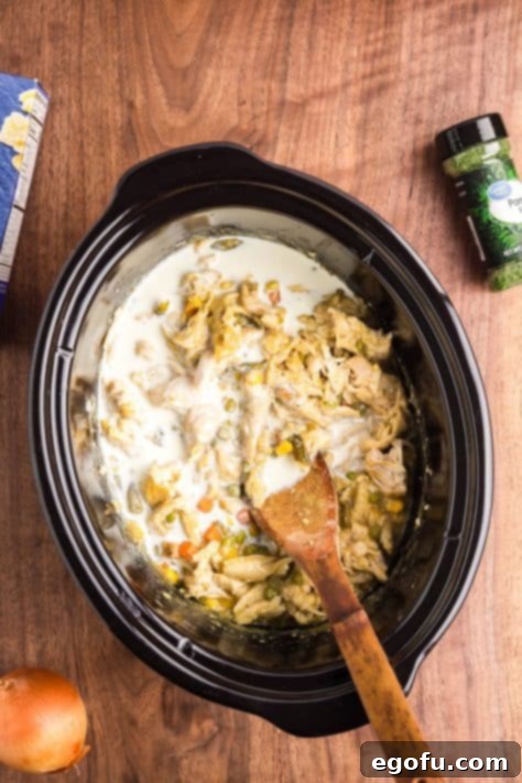 Ultimate Slow Cooker Chicken Pot Pie Pasta 13 Heavy cream being added to a Crockpot mixture.