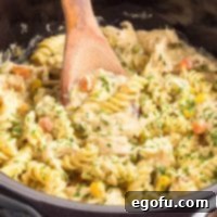 Ultimate Slow Cooker Chicken Pot Pie Pasta 9 Close up looking at a Crock Pot Chicken Pot Pie Pasta dish with a wooden utensil in it.