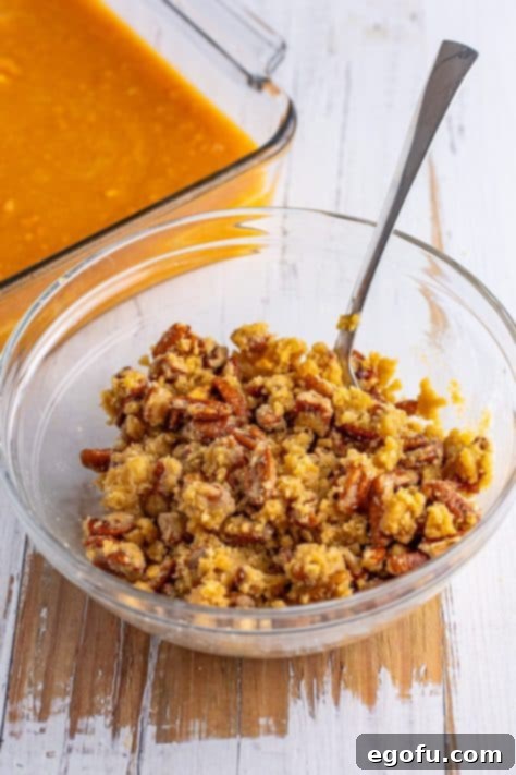 A bowl of melted butter, brown sugar, flour, and chopped pecans, forming crumbles.