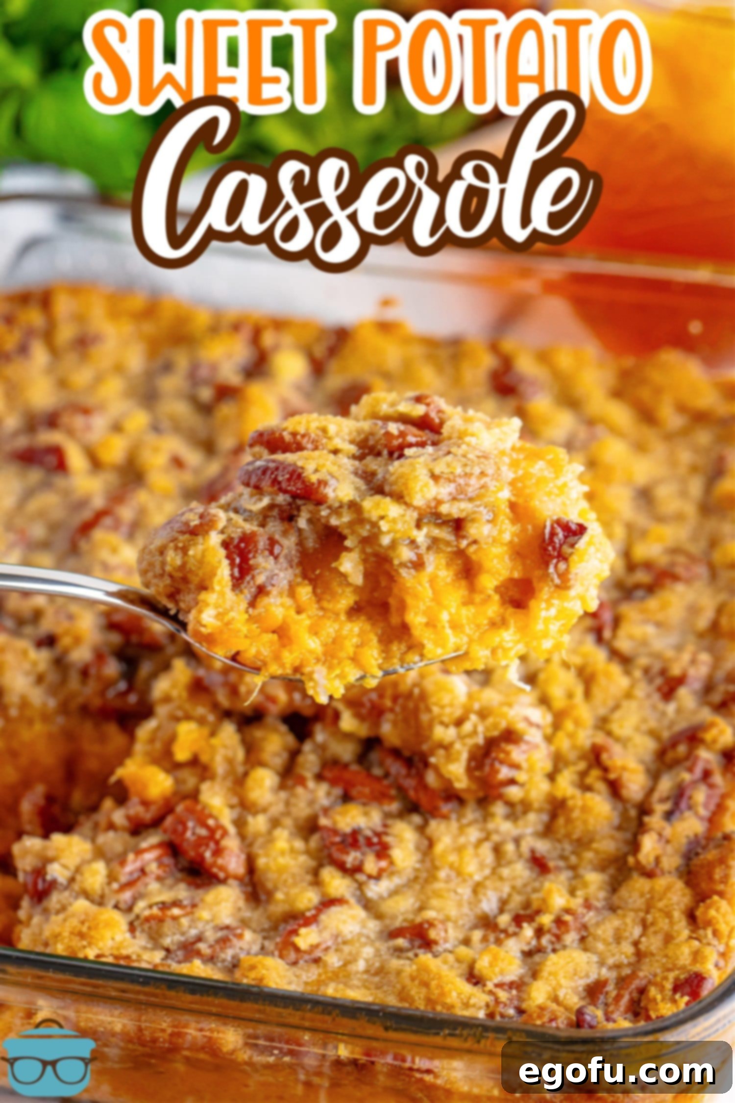 A serving of Sweet Potato Casserole held above the rest of the dish, showcasing its perfect texture and golden topping.