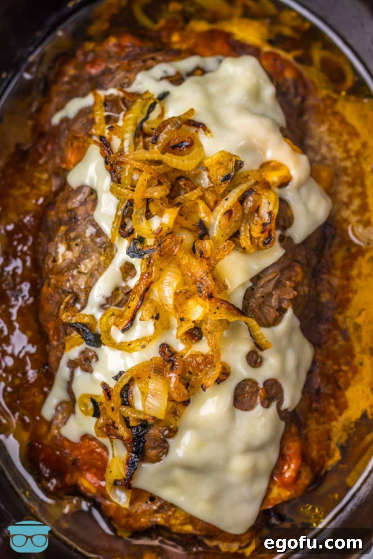 Looking down on a Slow Cooker French Onion Meatloaf with all the toppings, showcasing its readiness to be served. 