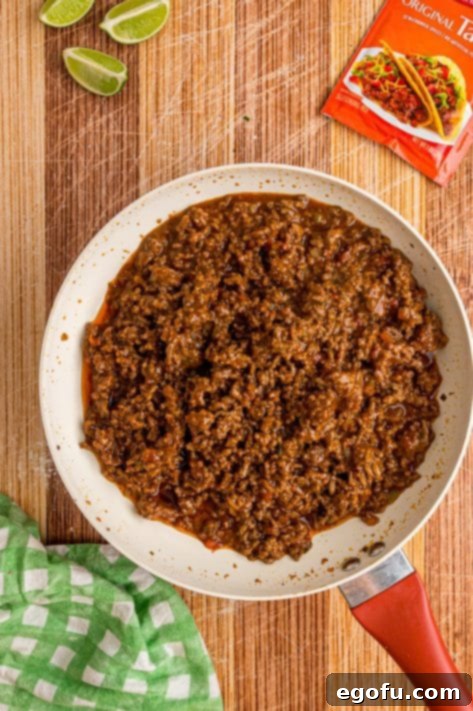 Ground beef, taco seasoning, water, and salsa simmering in a skillet.