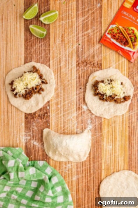 Beef and cheese pockets being folded and crimped to seal.