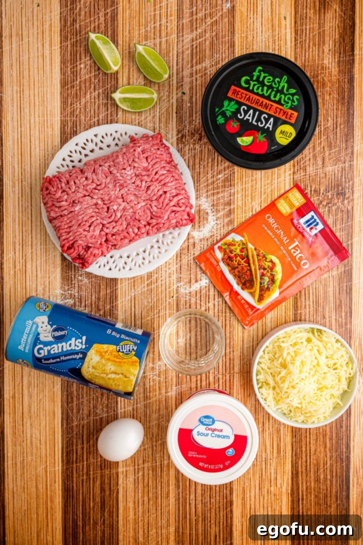 Display of ingredients: ground beef, biscuit dough, taco seasoning, egg, water, salsa, shredded cheese.