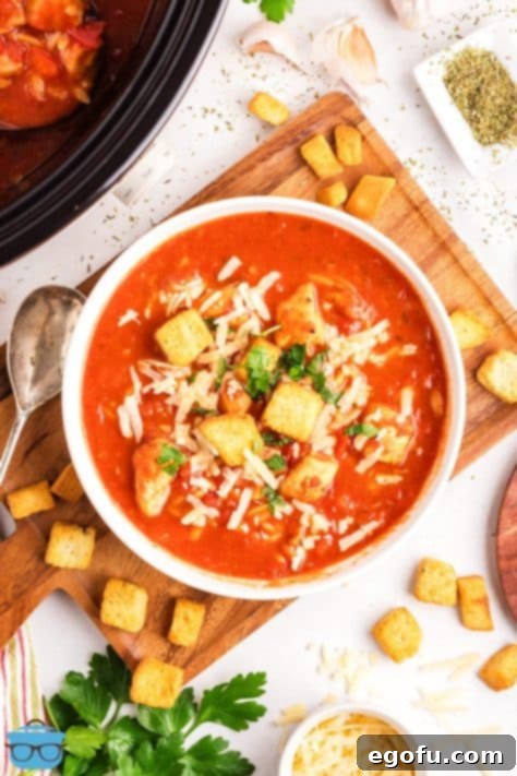 A large, finished bowl of garnished Slow Cooker Chicken Parmesan Soup, topped with croutons, Parmesan, and parsley.