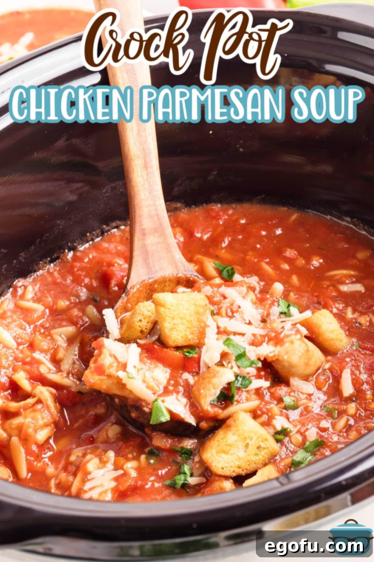 A wooden ladle scooping a hearty portion of Slow Cooker Chicken Parmesan Soup from a pot.