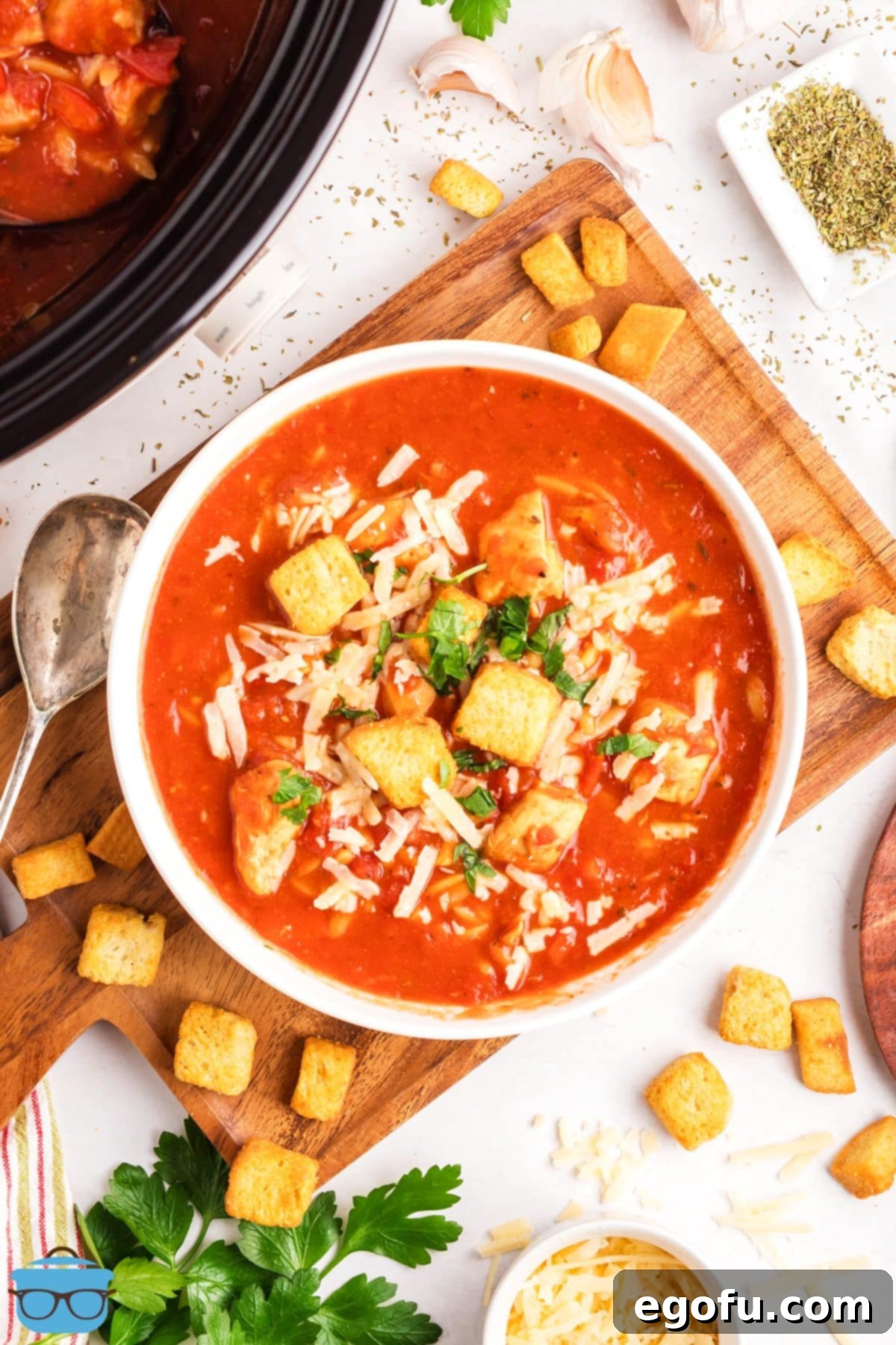 Looking down on a large, beautifully garnished bowl of Slow Cooker Chicken Parmesan Soup, ready to be enjoyed.