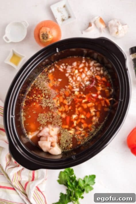 All the initial ingredients for Slow Cooker Chicken Parmesan Soup are combined in a Crockpot, ready for cooking.