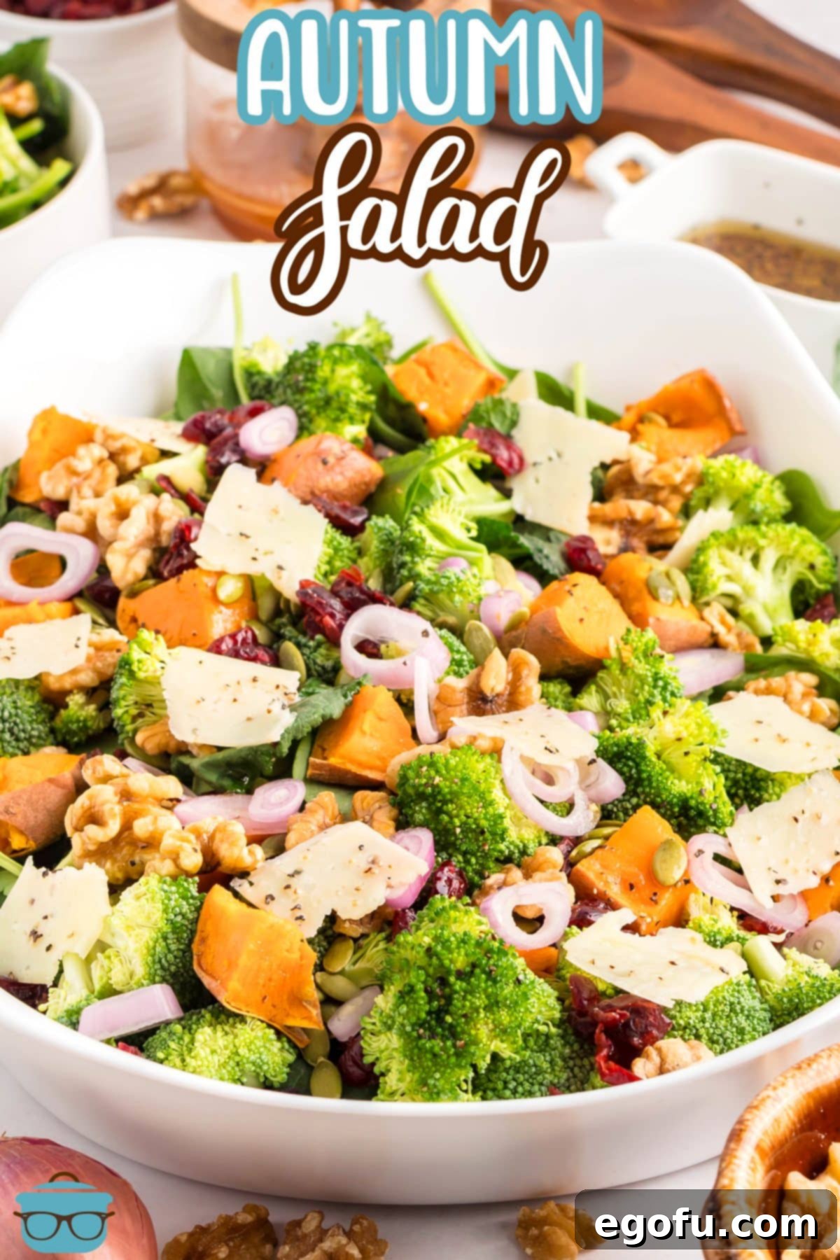 A white serving bowl filled with the beautiful Autumn Salad, showcasing its vibrant mix of greens, sweet potatoes, and cranberries, ready to be served at a fall gathering.