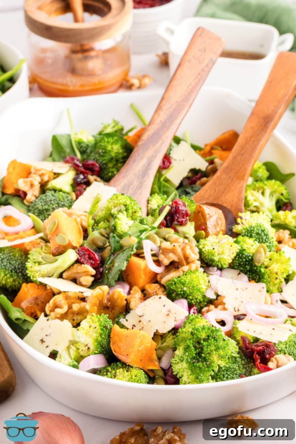 A set of elegant salad tongs resting in a freshly tossed bowl of Autumn Salad, perfectly coated with vinaigrette and ready to be served and enjoyed.