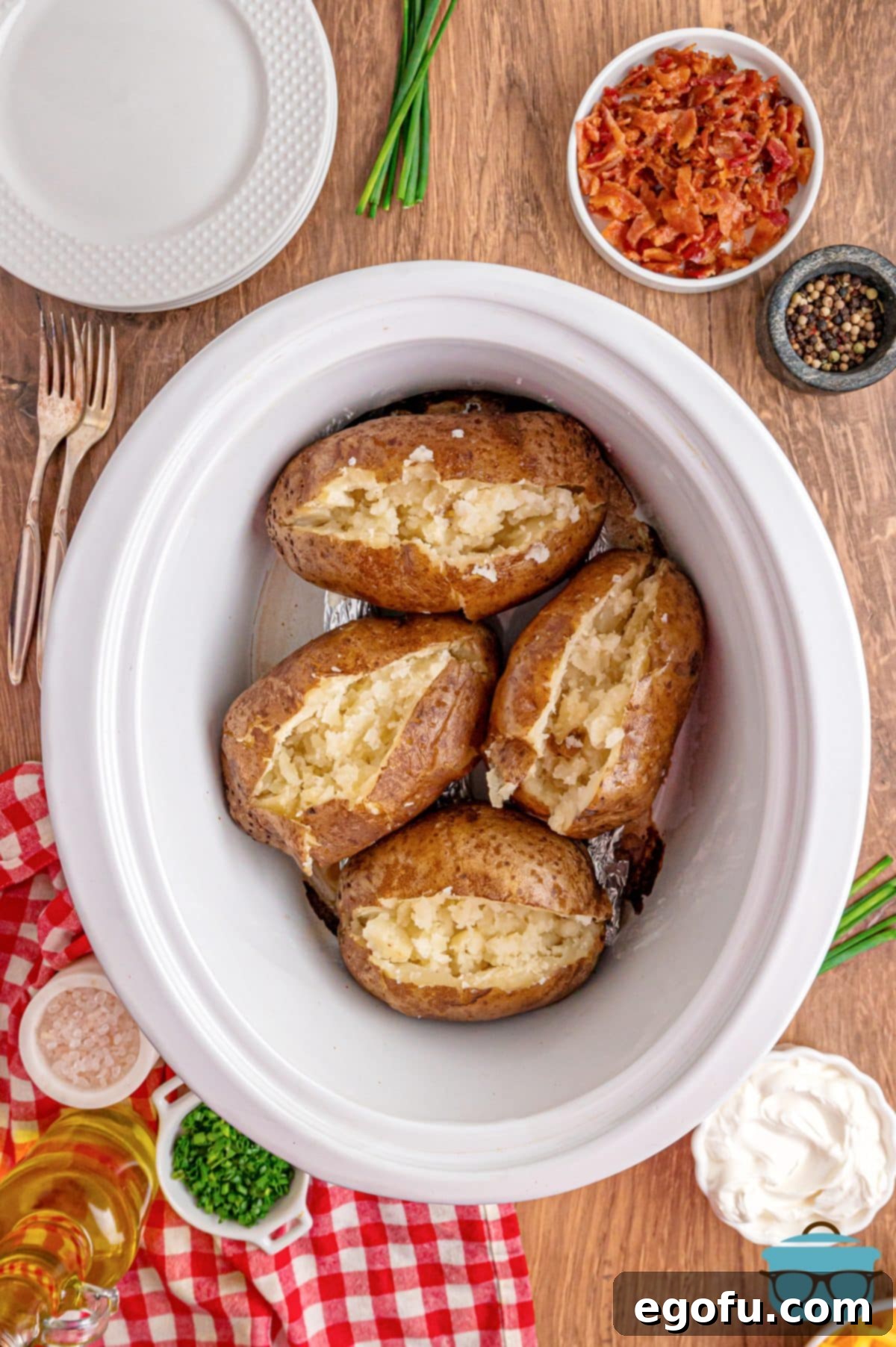 Looking down on a few Crock Pot Baked Potatoes sliced open with toppings.