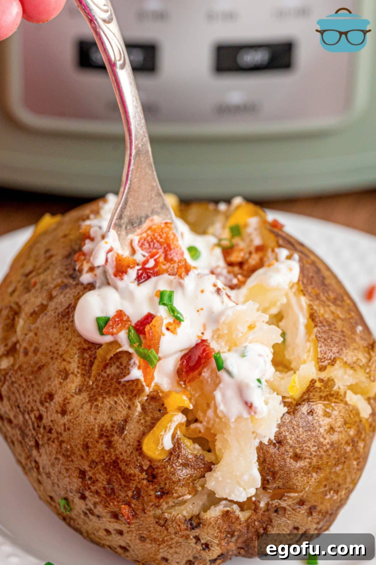 An overflowing Crock Pot Baked Potato with a fork in the topping, ready to eat.