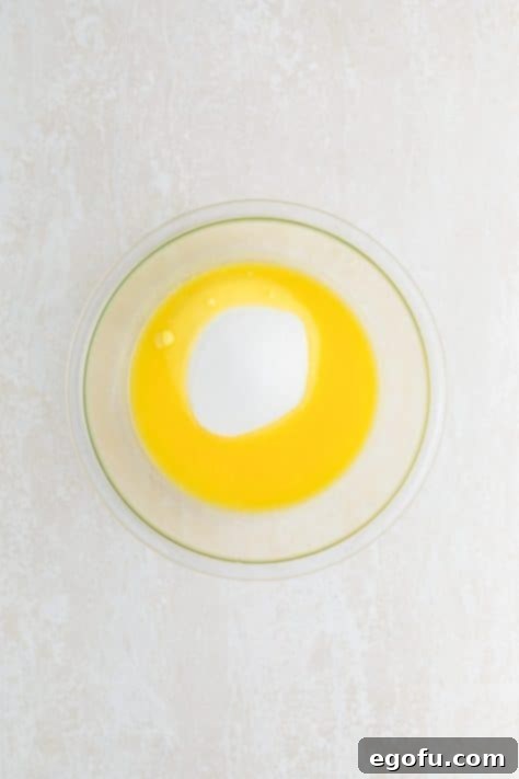 Melted butter and sugar being mixed in a bowl.