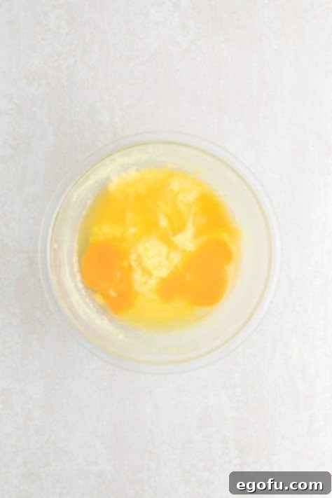 Lemon juice and eggs being added to the sugar and butter mixture in a bowl.