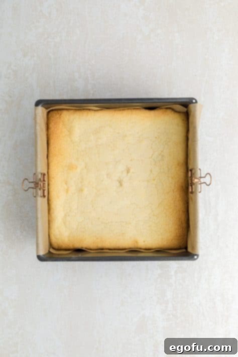 Freshly baked lemon brownies cooling in a lined baking dish.