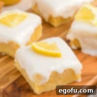Closely looking down on a few Homemade Lemon Brownies with glaze, highlighting their vibrant color and glossy topping.