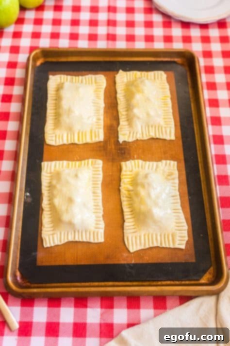 Crimped and egg wash coated unbaked Puff Pastry Apple Pies.