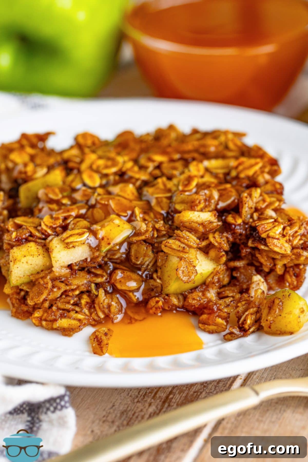 A freshly baked slice of Apple Baked Oatmeal, served on a plate and beautifully drizzled with extra caramel sauce, highlighting its warm, inviting appeal.