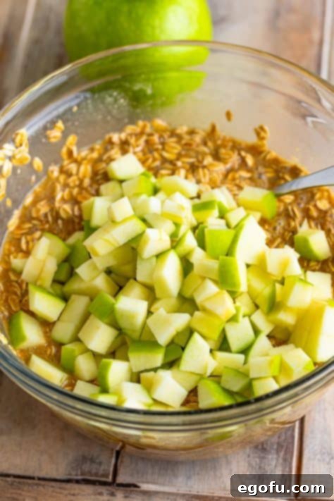 Apples being added to unbaked oatmeal mixture.