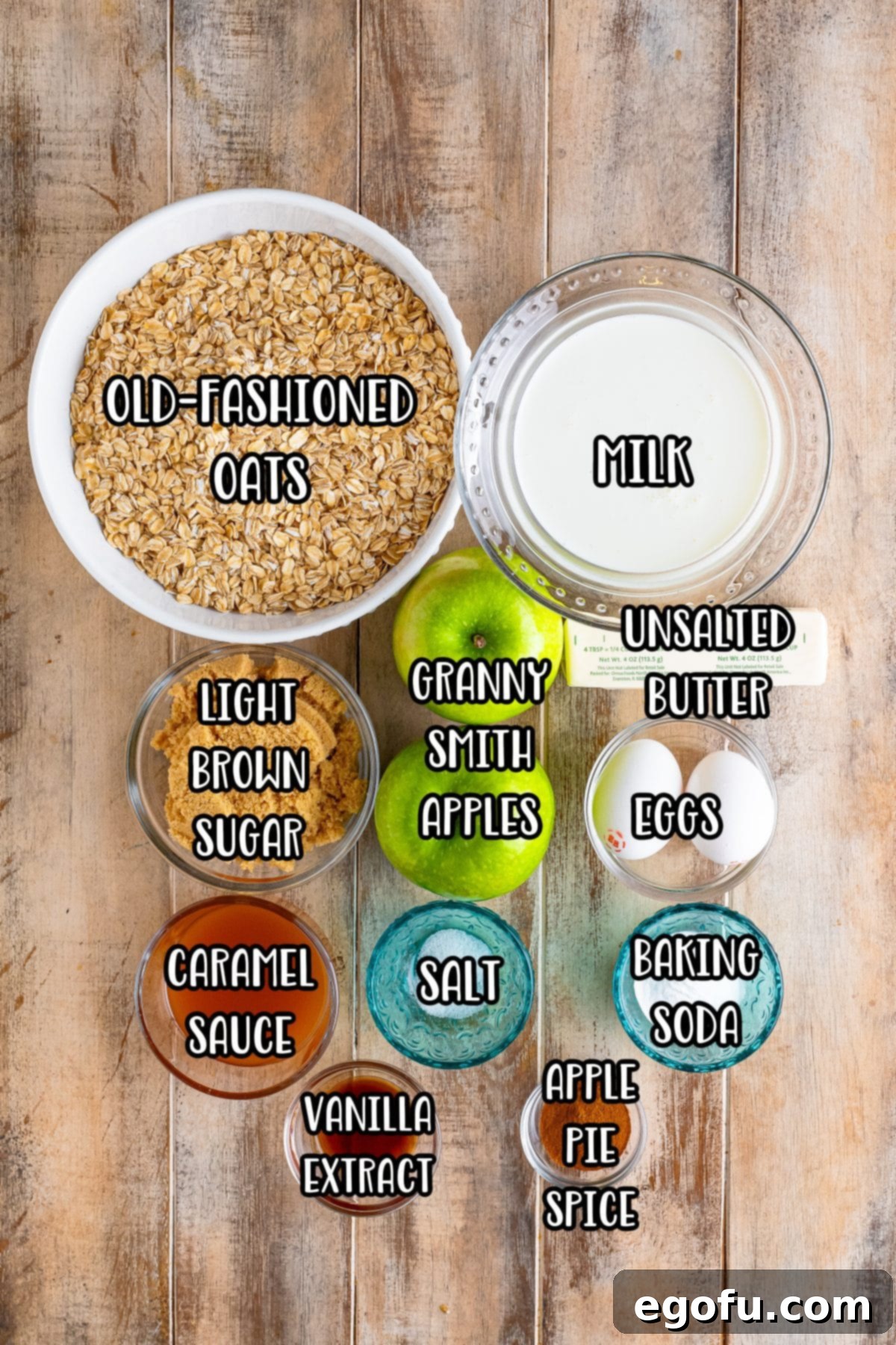 A visual display of all the key ingredients for Apple Baked Oatmeal: old-fashioned oats, milk, Granny Smith apples, eggs, unsalted butter, light brown sugar, caramel sauce, salt, baking soda, apple pie spice, and vanilla extract.