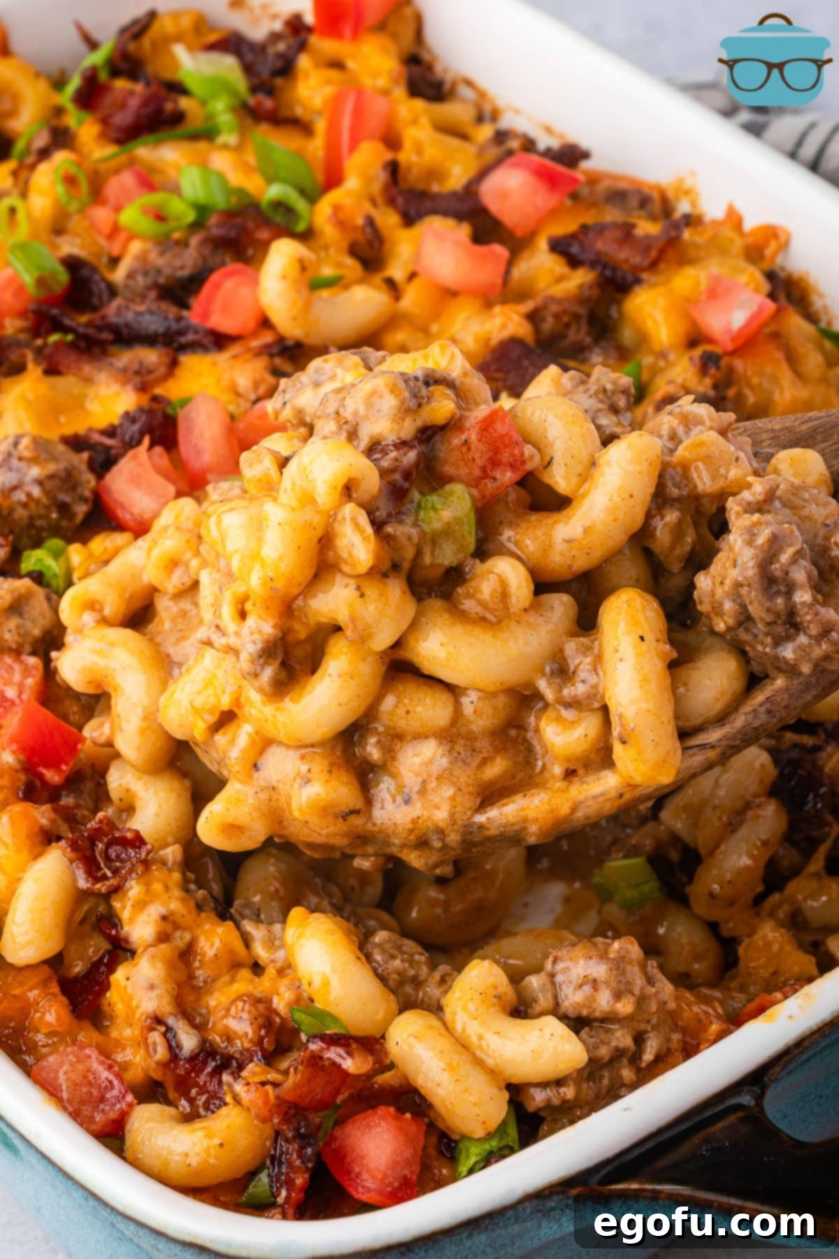 Cheesy Bacon Burger Bake 2 A generous scoop of Bacon Cheeseburger Casserole being lifted from a baking dish, showcasing melted cheese, savory beef, crispy bacon, and tender pasta.