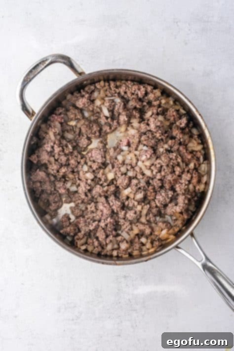 Cheesy Bacon Burger Bake 6 Sizzling ground beef and fragrant diced yellow onions cooking in a skillet, forming the savory foundation for the casserole.