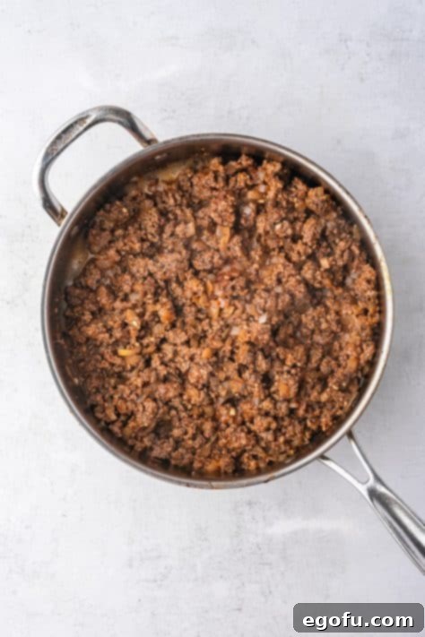 Cheesy Bacon Burger Bake 7 The ground beef and onion mixture seasoned with ketchup, mustard, garlic, and spices, before liquids are added.
