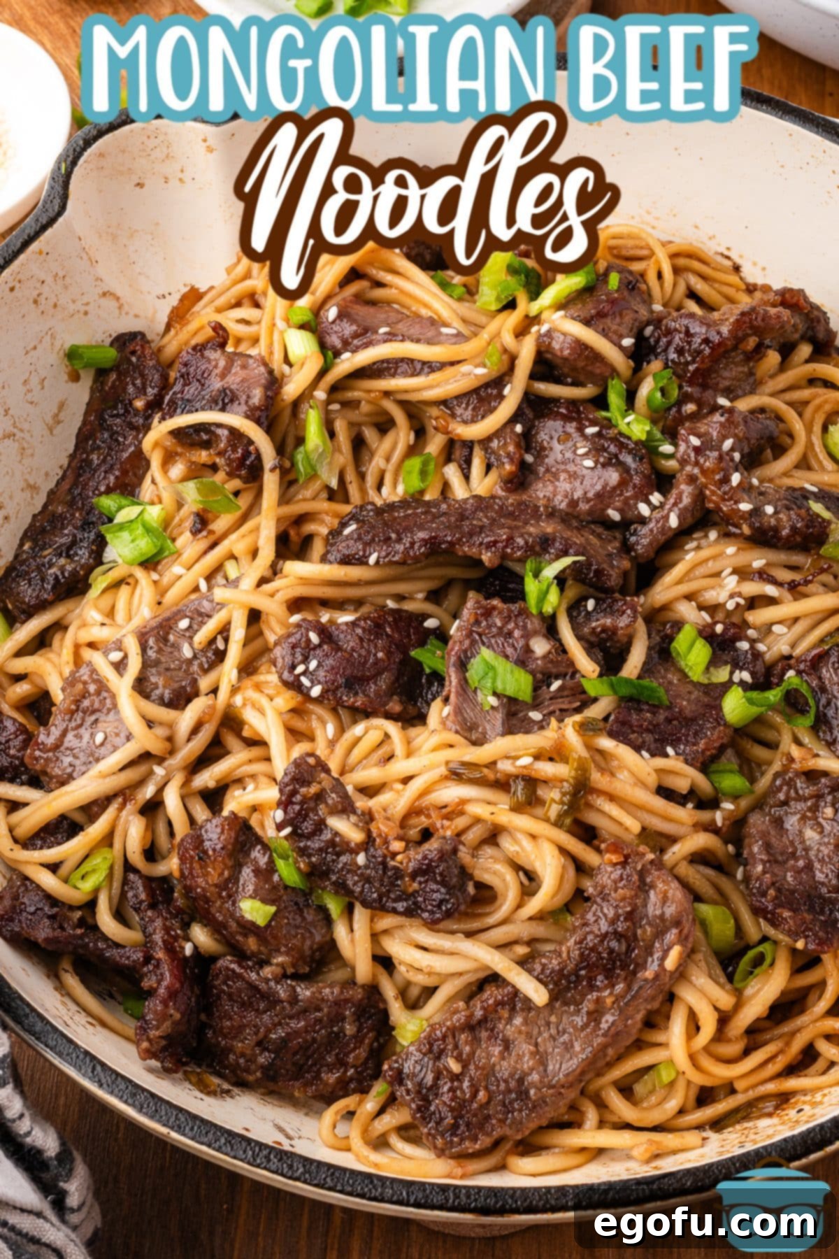 An overhead view of a large, steaming pot of Mongolian Beef Noodles, showcasing the rich sauce and vibrant green onions.