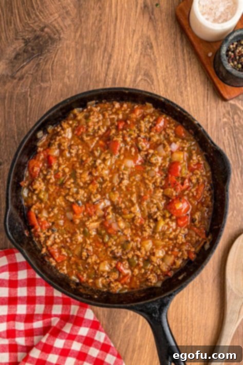 Ground beef, onion, chiles, tomatoes, and taco seasoning with water in a skillet.
