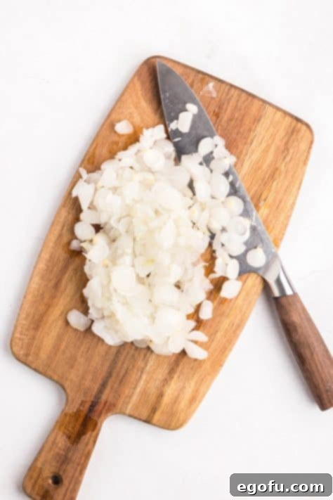 Diced cocktail onions on a cutting board with a knife.