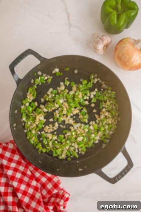 Diced green peppers, onions, and garlic in a skillet.