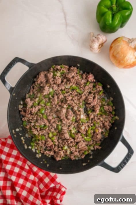 Ground beef and veggies cooking in a skillet.