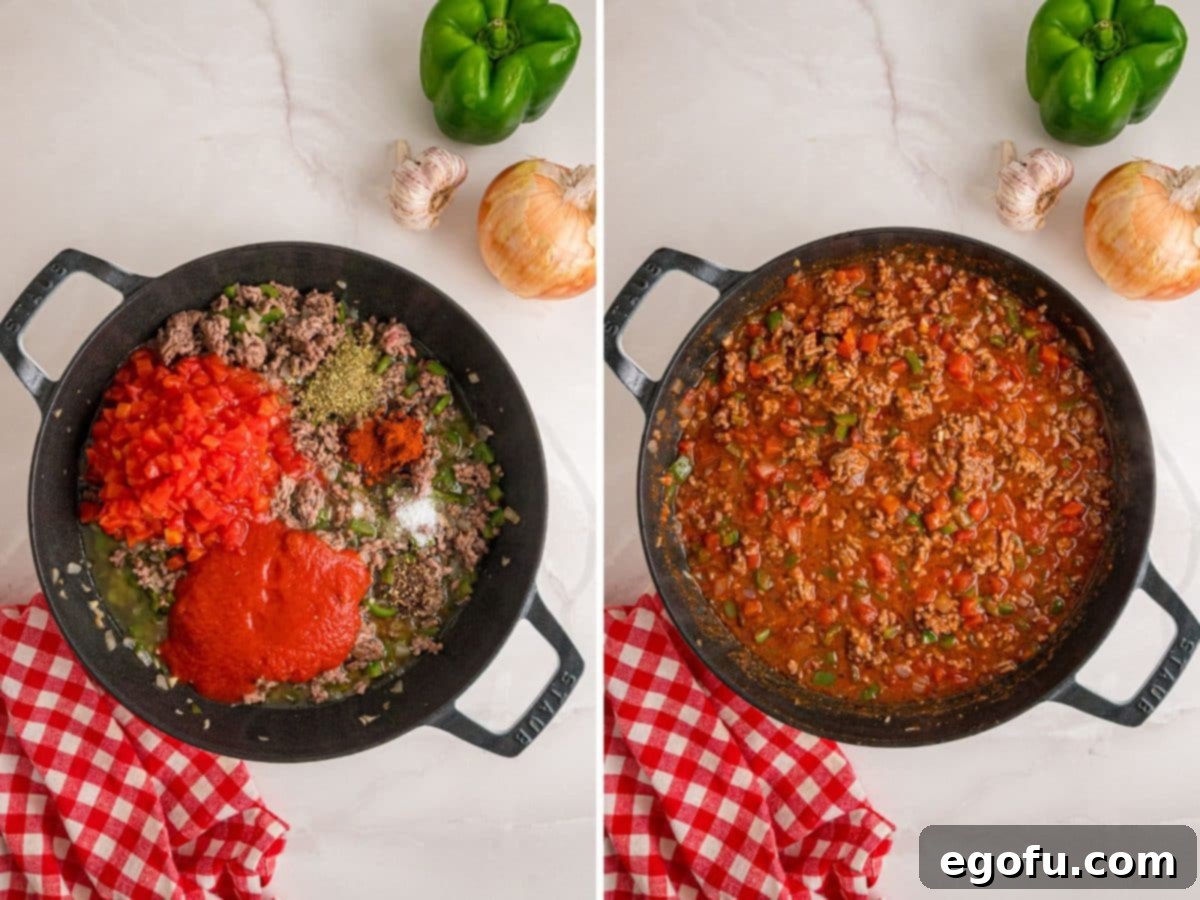 Diced tomatoes, rich tomato sauce, and fragrant spices being added to the browned ground beef and vegetable mixture in a skillet to form the casserole's flavorful base.