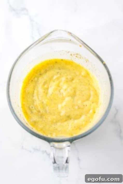 A mixing cup with cream of chicken soup, cream of celery soup, milk, garlic powder, poultry seasoning, onion powder and pepper.