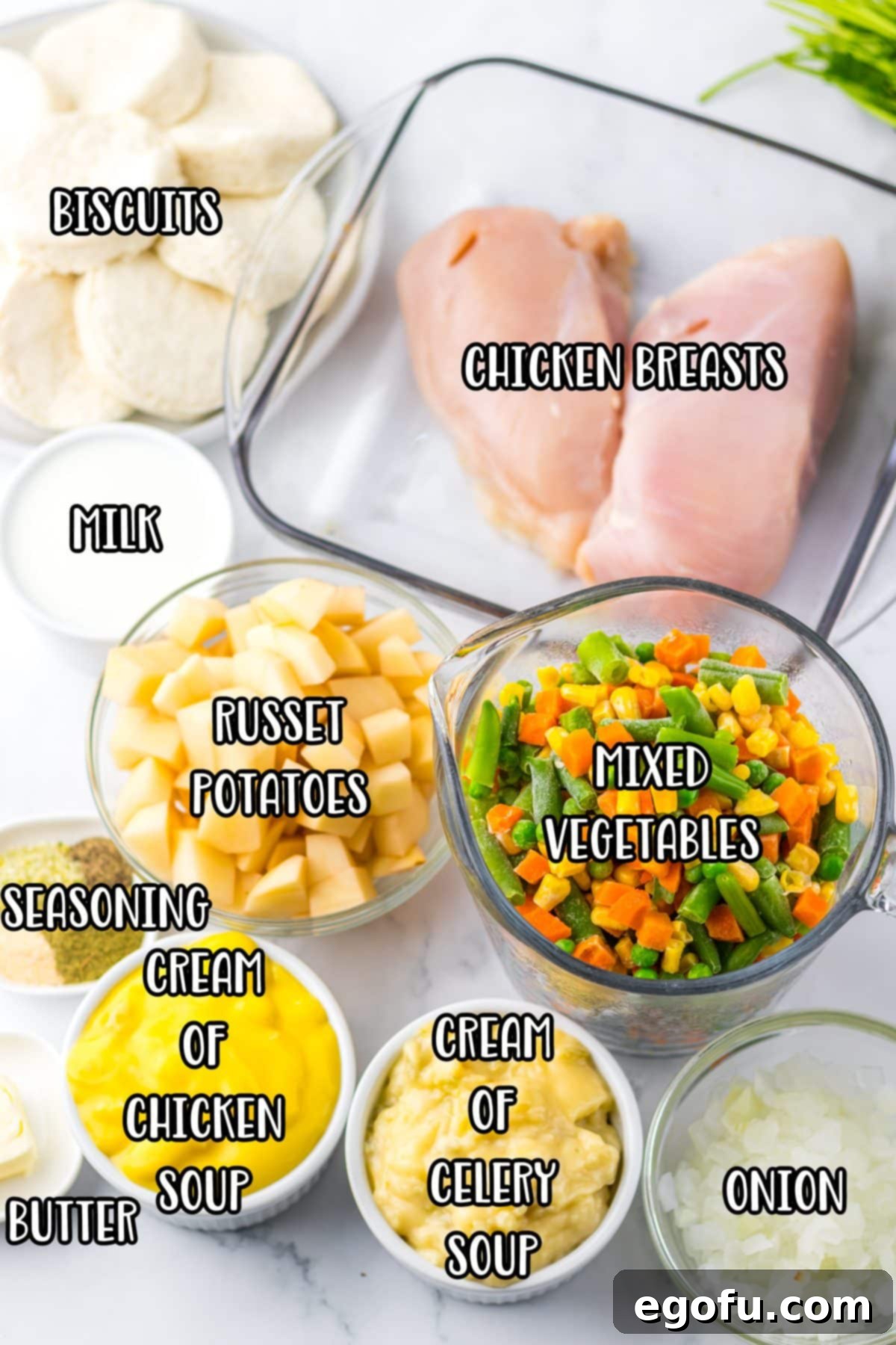 Chicken breast, onion, potatoes, frozen mixed veggies, cream of chicken soup, cream of celery soup, milk, garlic powder, poultry seasoning, onion powder, black pepper, biscuit dough, butter, and parsley.