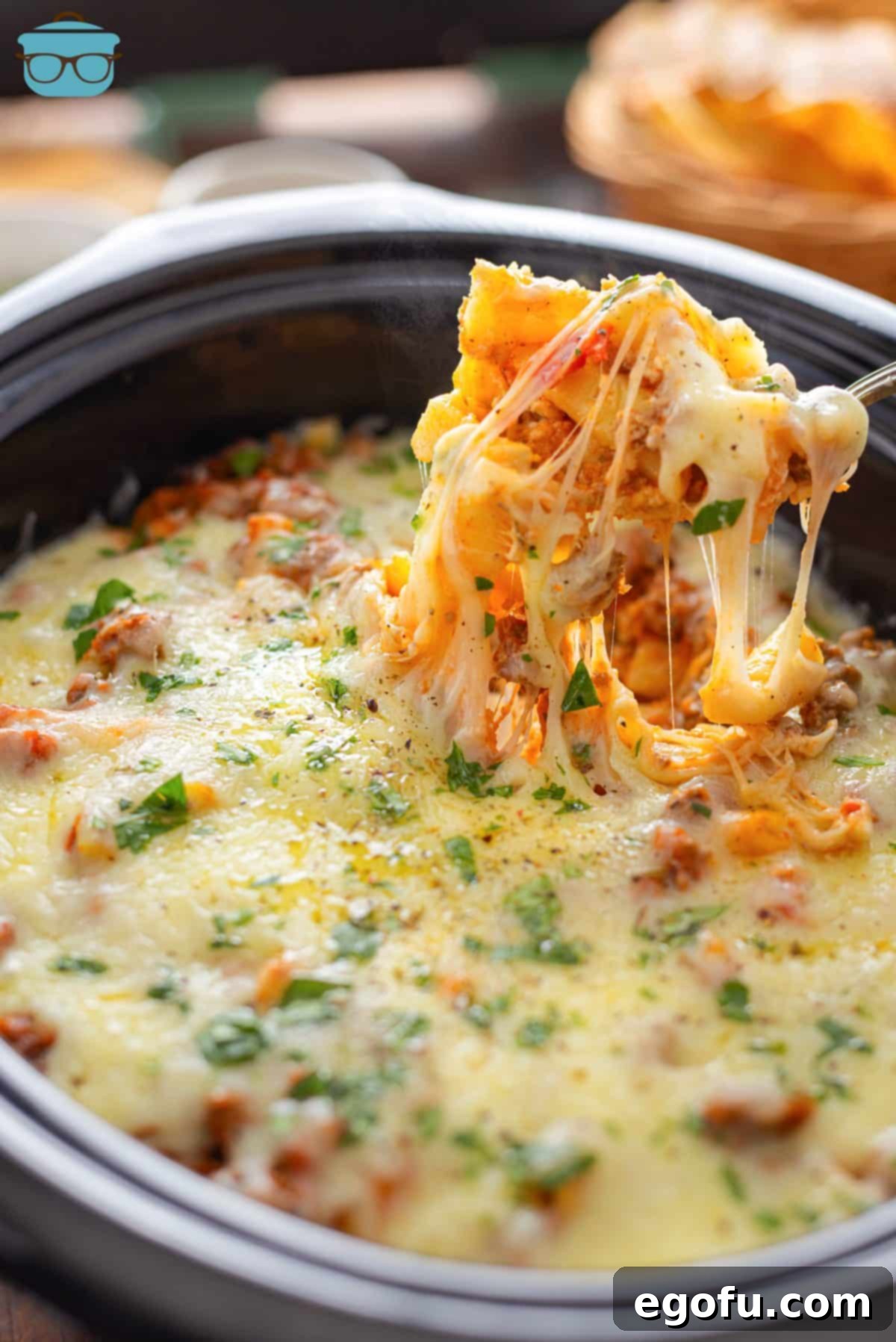 A large serving spoon scooping a generous portion of cheesy, piping hot Crock Pot Baked Ziti from the slow cooker, showcasing its rich layers and perfectly melted cheese.